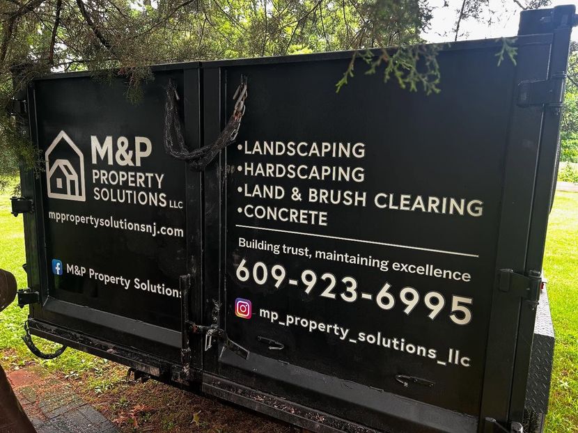Black dumpster with M&P Property Solutions logo and contact info for landscaping and concrete services.