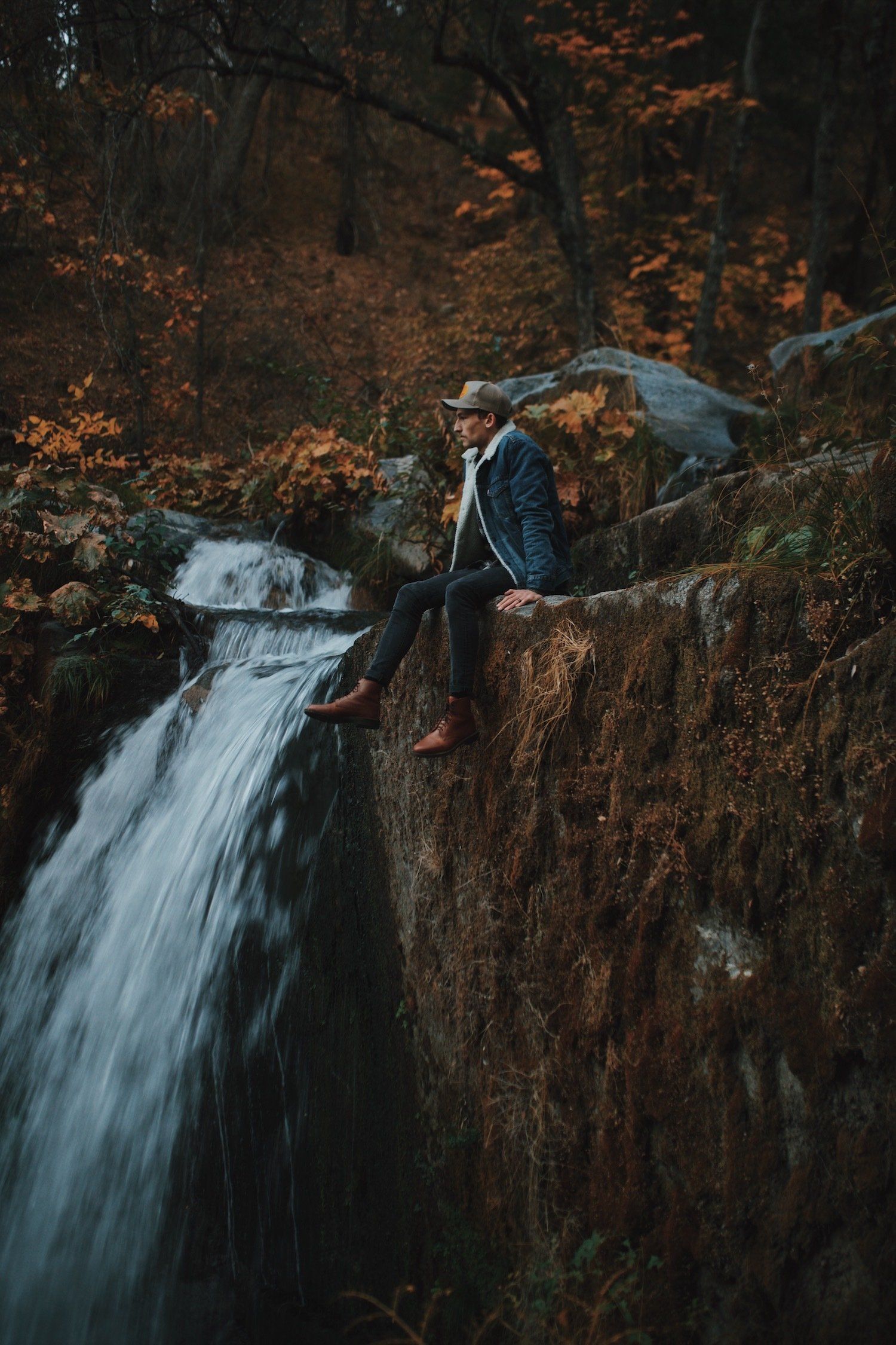 An image of a man sitting on the ledge of a waterfall at Lassen National Park.