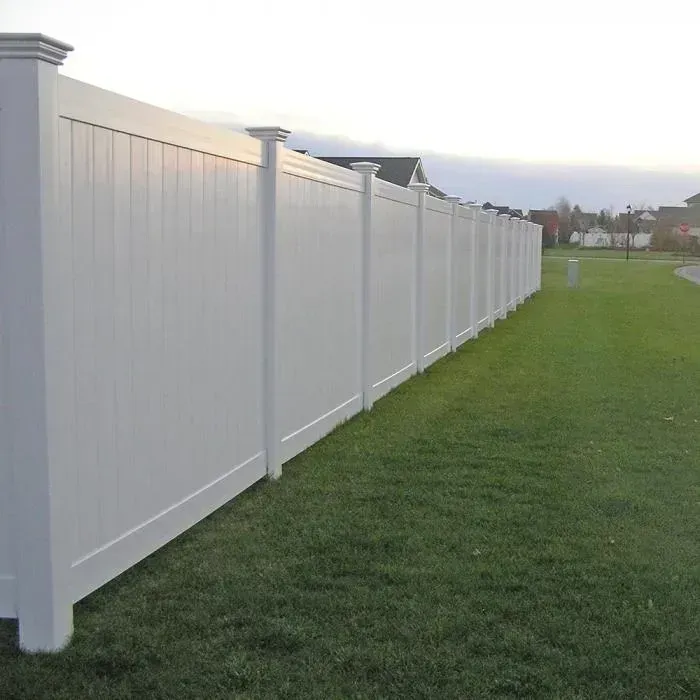 White vinyl fence along green grass in a residential area.