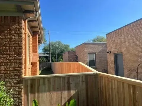 A view of brick buildings with a wooden fence under a clear blue sky.