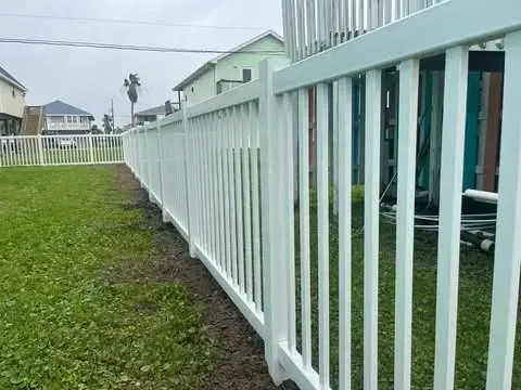 White picket fence along a grassy yard, houses in background.