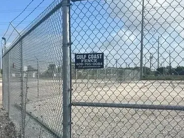 Chain-link fence with barbed wire. A sign reads