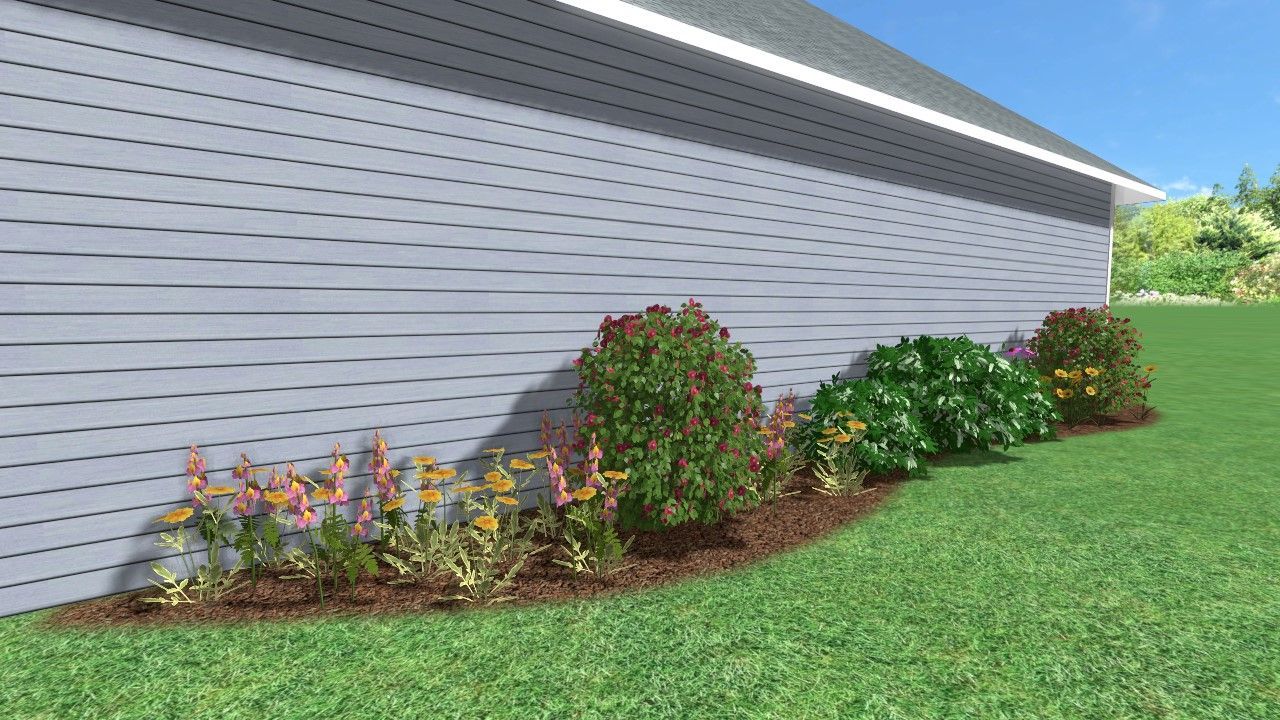Landscaped bed with colorful plants against a gray-sided house.