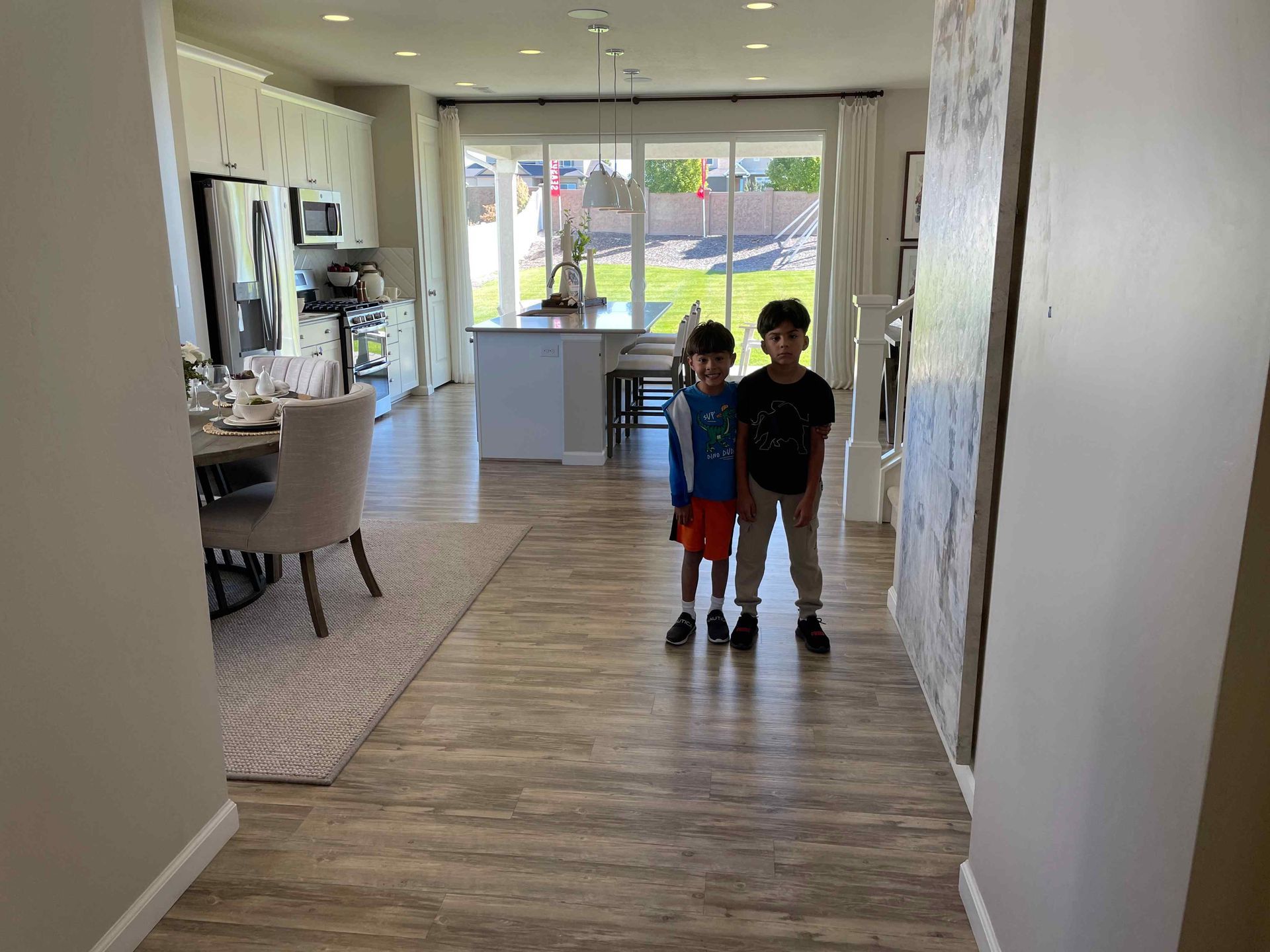 Two young boys are standing in a hallway in a house.