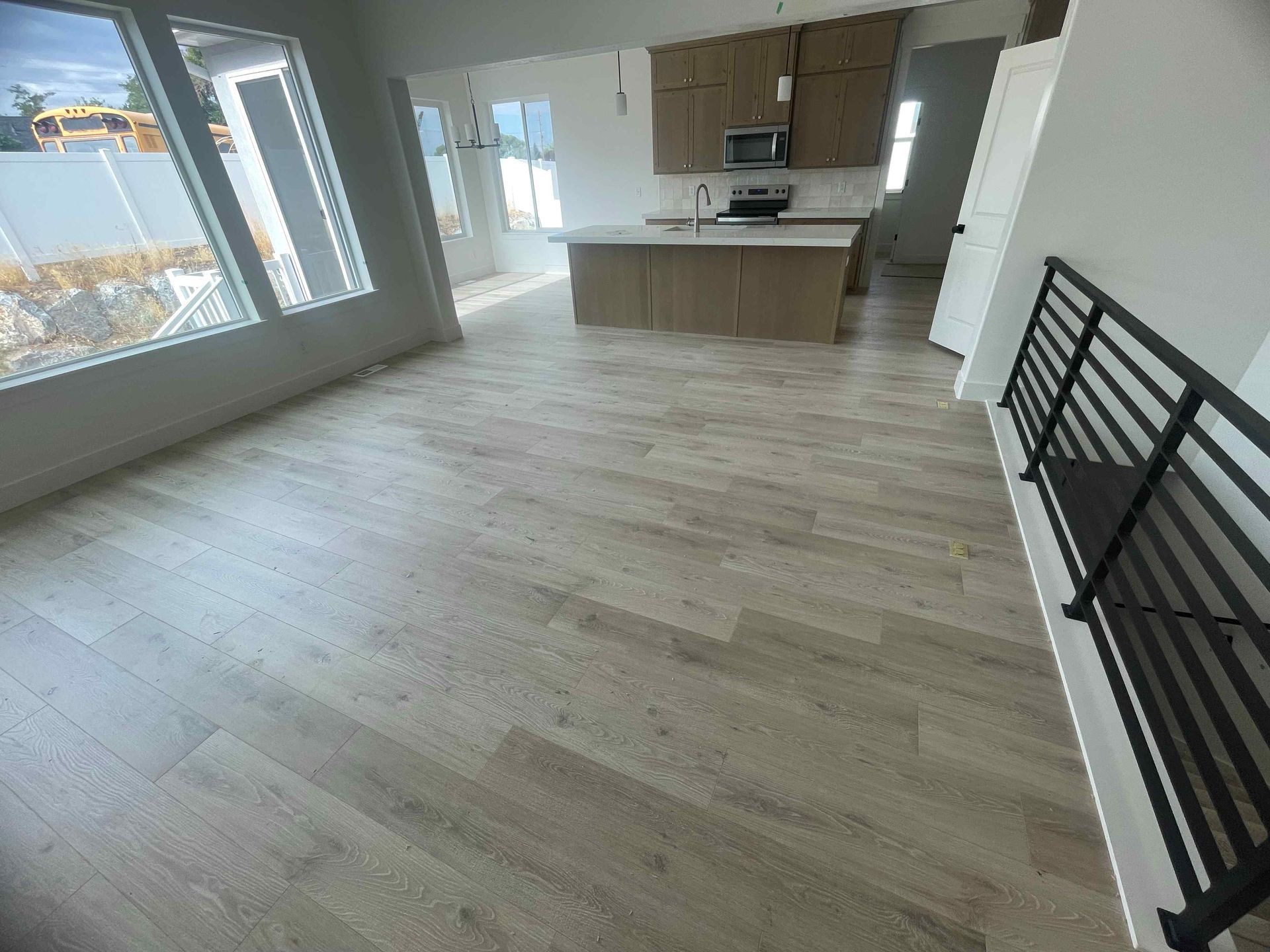 A living room with hardwood floors and a kitchen in the background.