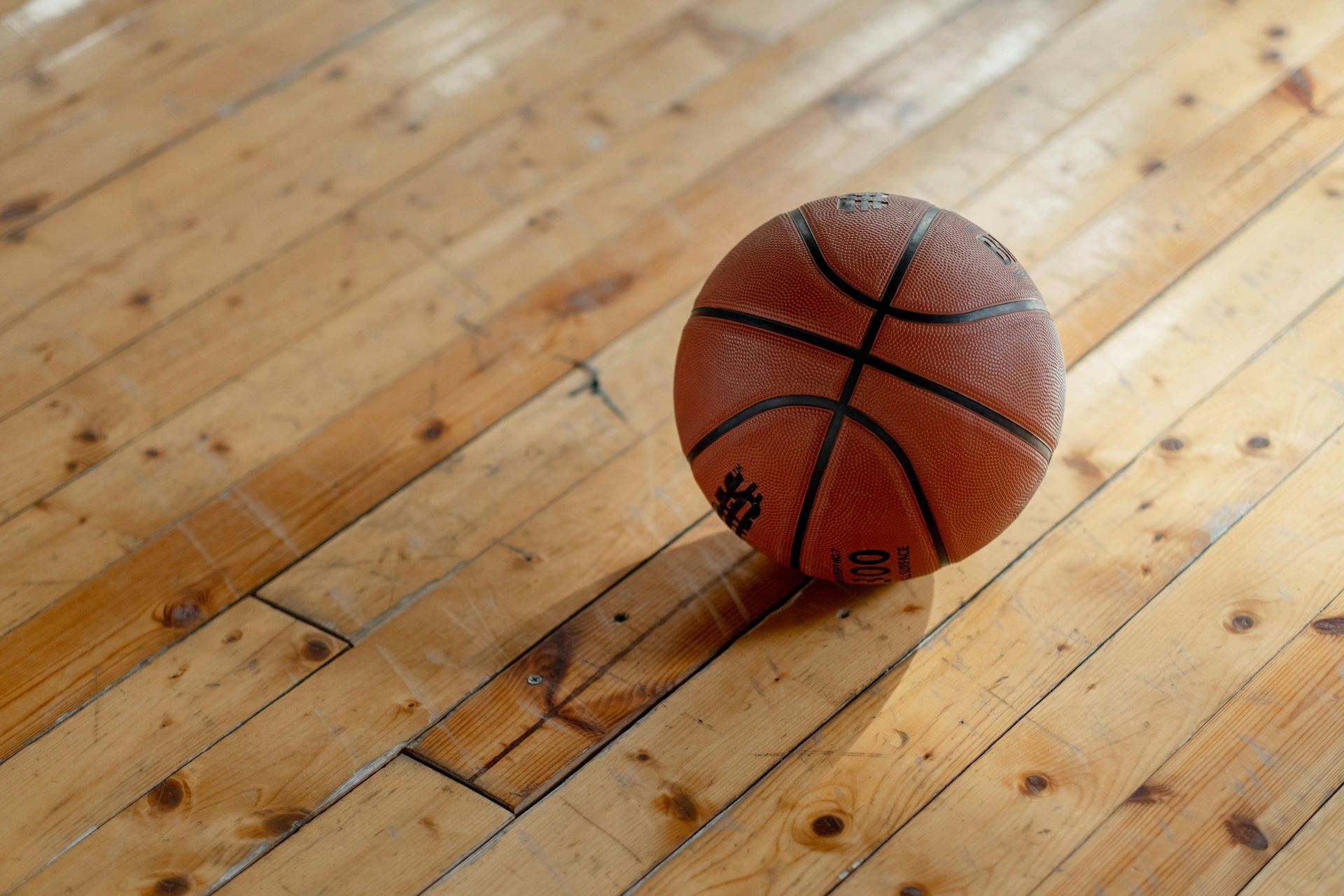 A basketball is sitting on a wooden floor.