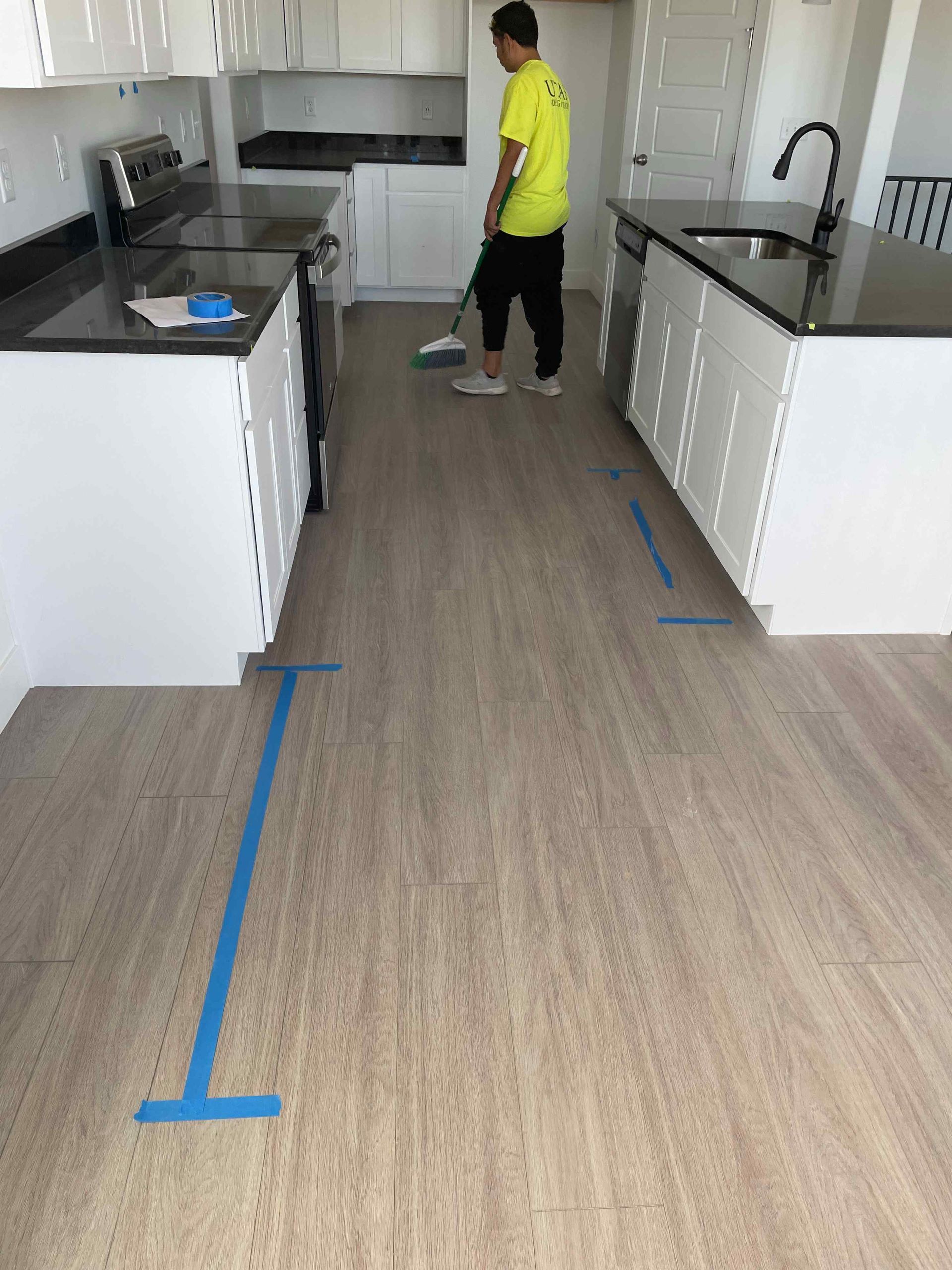 A man is cleaning the floor of a kitchen with a mop.