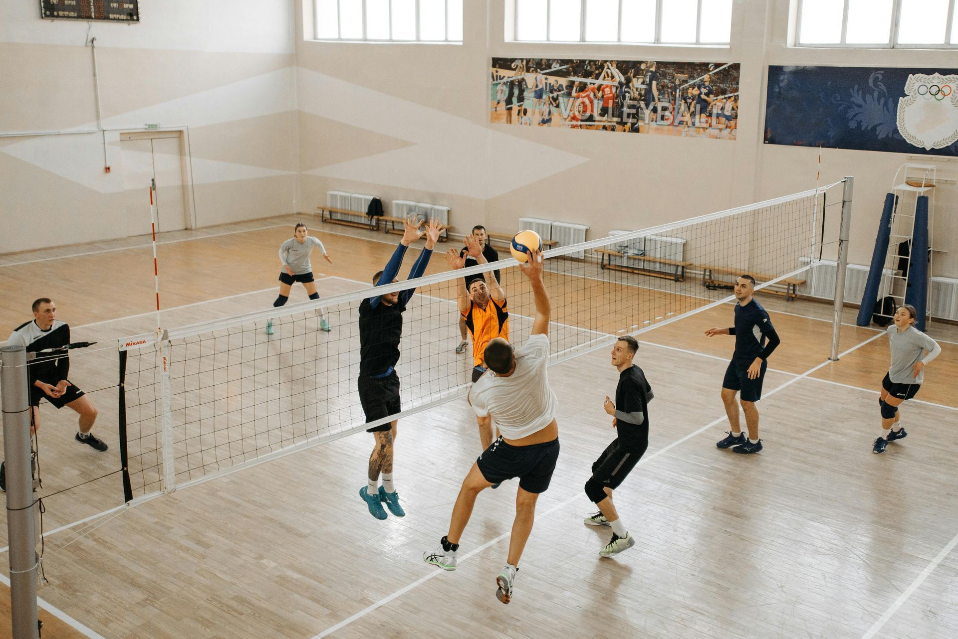 A group of people are playing volleyball in a gym.