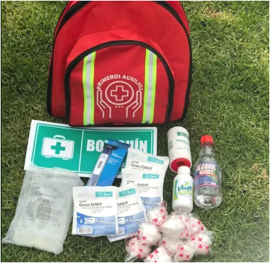 Un botiquín de primeros auxilios está sobre el césped junto a un cartel que dice 