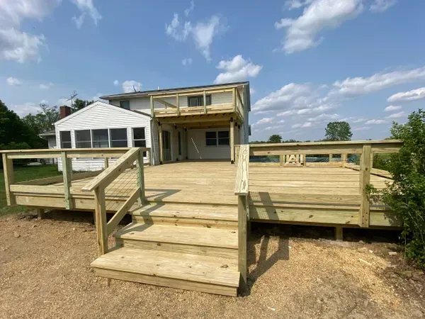 A large wooden deck with stairs leading to it is in front of a house. A large wooden deck with stairs leading to it is in front of a house.