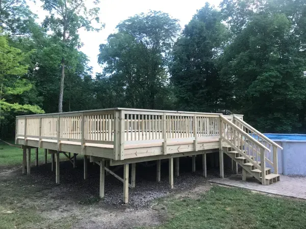 A large wooden deck with stairs next to a pool.
