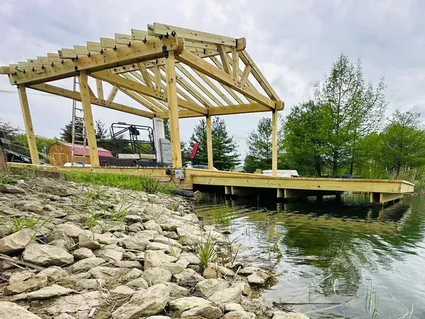 A wooden structure is being built next to a body of water. A wooden structure is being built next to a body of water.