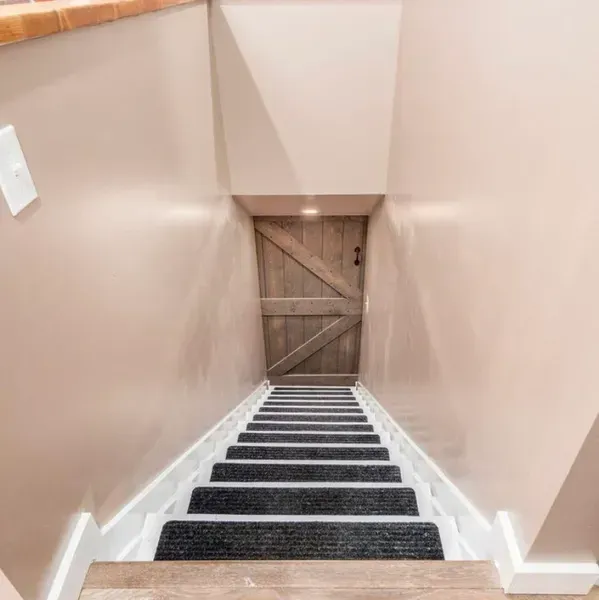 A set of stairs leading up to a wooden door in a basement. A set of stairs leading up to a wooden door in a basement.