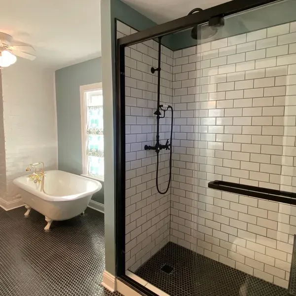 A bathroom with a tub and a shower with a glass door. A bathroom with a tub and a shower with a glass door.