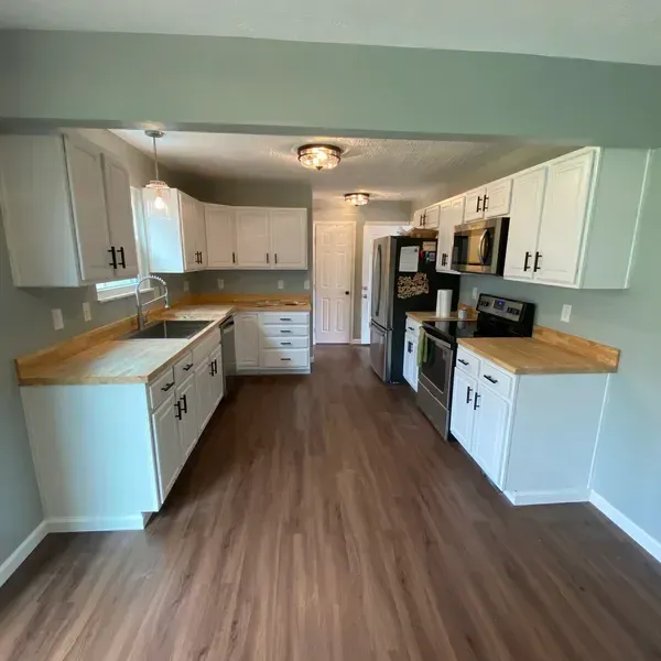 A kitchen with a stove , oven , microwave and shelves. A kitchen with a stove , oven , microwave and shelves.