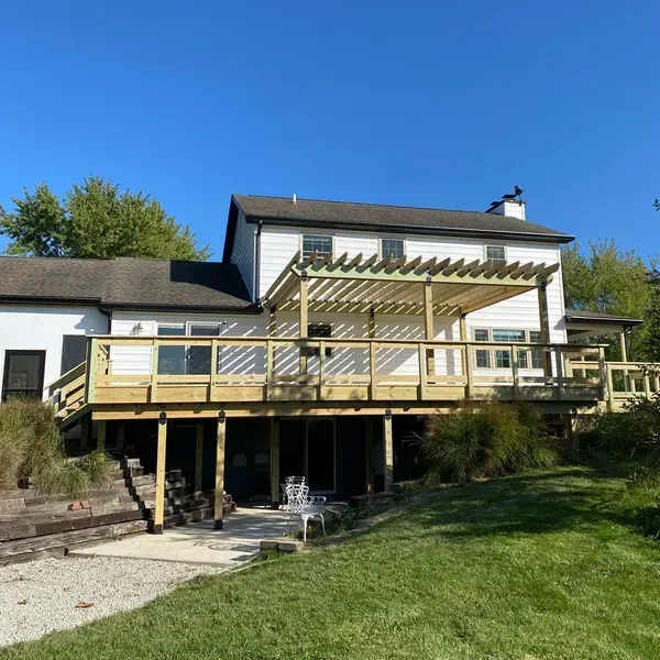 The back of a house with a large wooden deck and pergola.