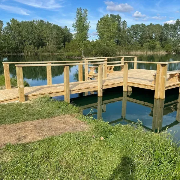 A wooden bridge over a body of water with trees in the background.