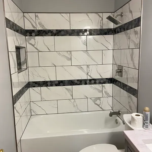 A bathroom with a bathtub , toilet , sink and shower.