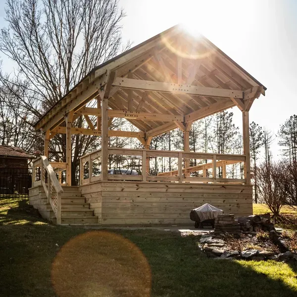 A wooden gazebo with stairs leading up to it A wooden gazebo with stairs leading up to it