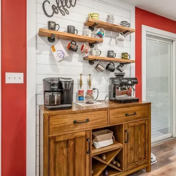 A coffee bar with a coffee maker , coffee mugs , and a wine rack. A coffee bar with a coffee maker , coffee mugs , and a wine rack.