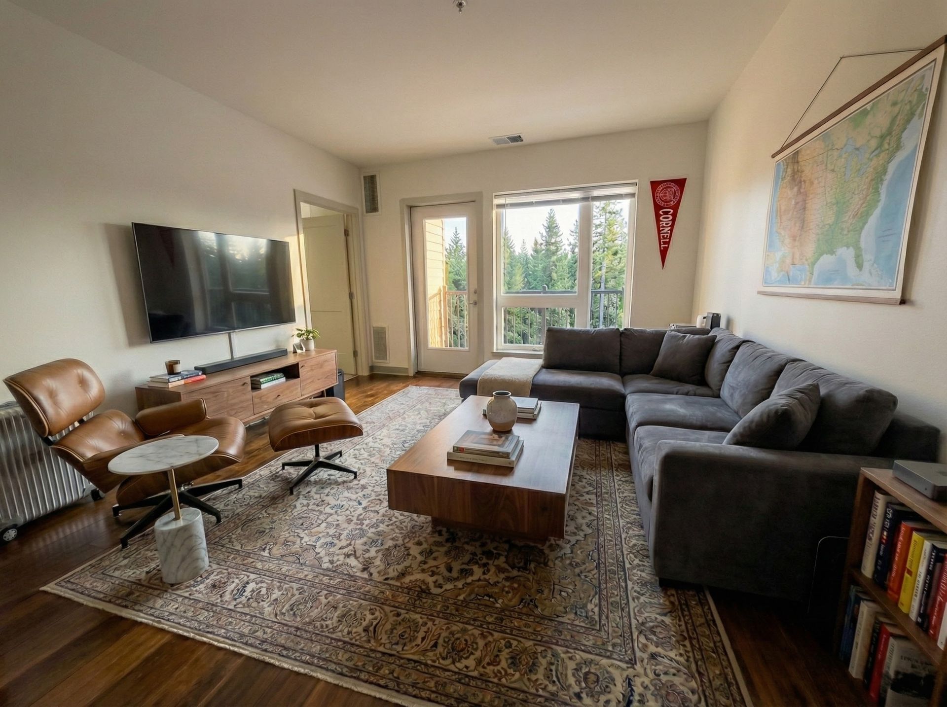 Living room with sectional sofa, TV, armchair, rug, and map on the wall.