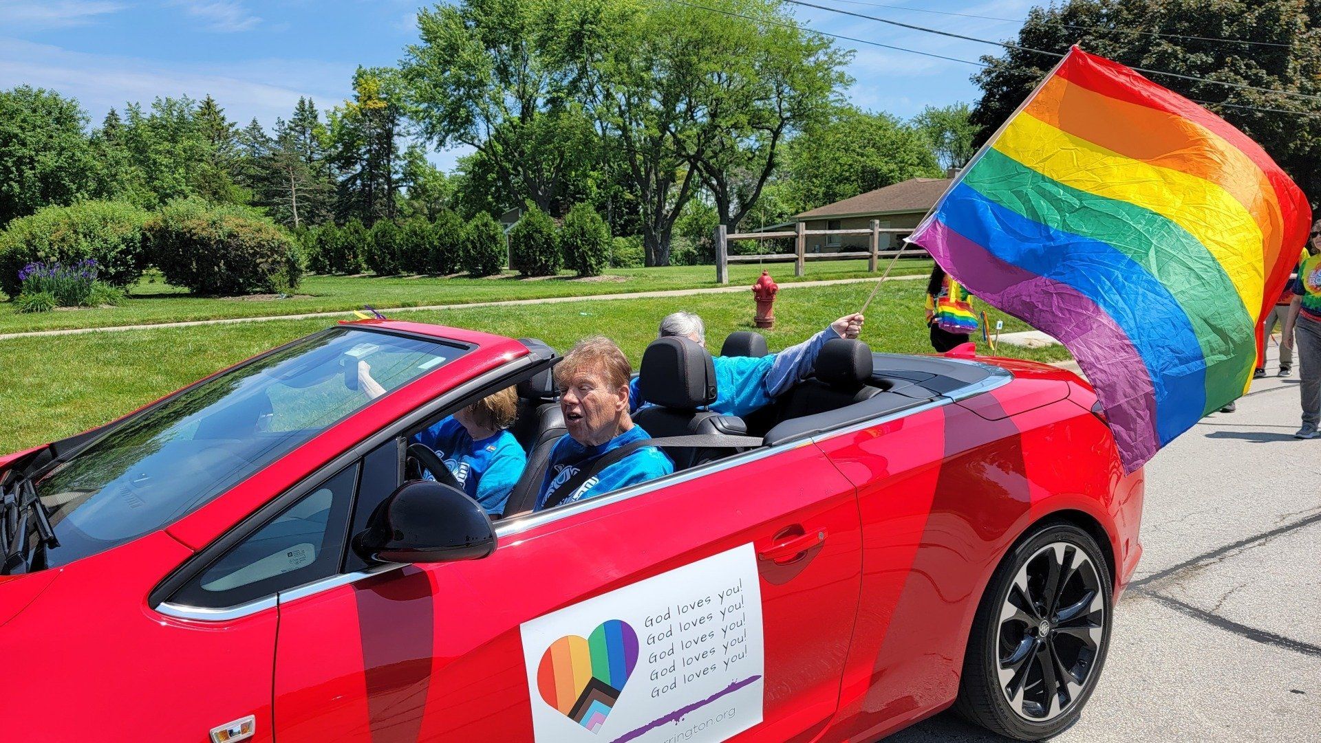 A red convertible car with a rainbow flag on the back.
