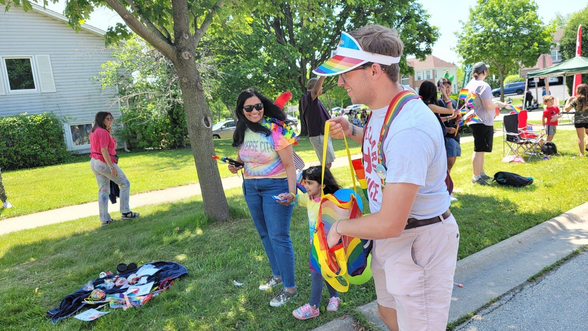 A man wearing a rainbow visor is standing next to a woman holding a balloon.