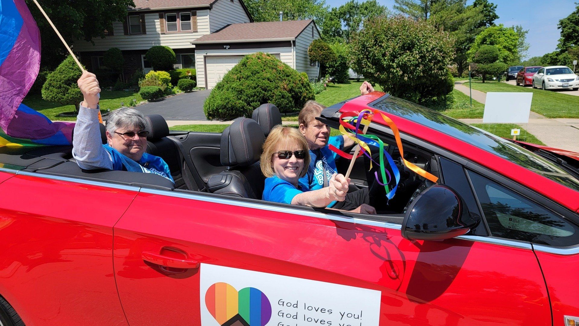 A group of people are riding in a red car in a parade.