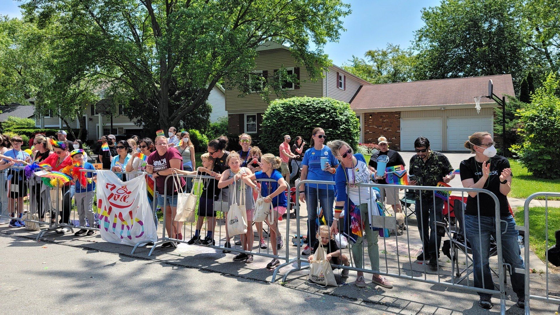 A large group of people are standing behind a fence watching a parade.