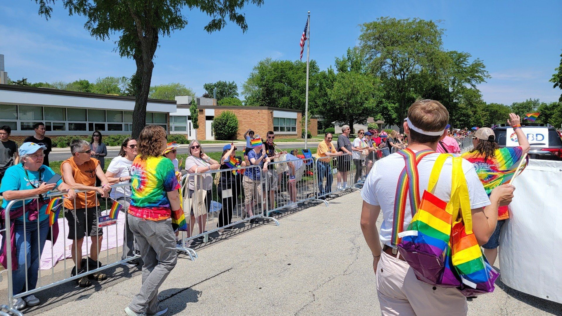 A group of people are standing behind a fence watching a parade.