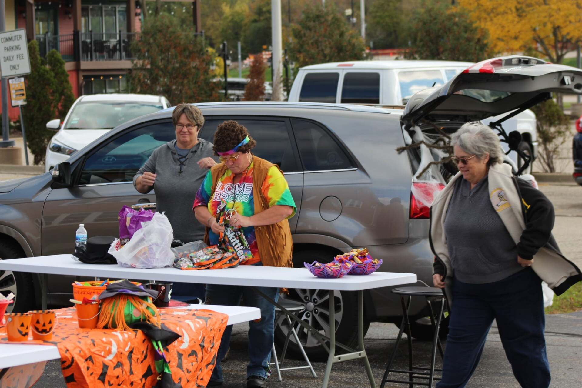 Two women are standing in front of a table with a car in the background.