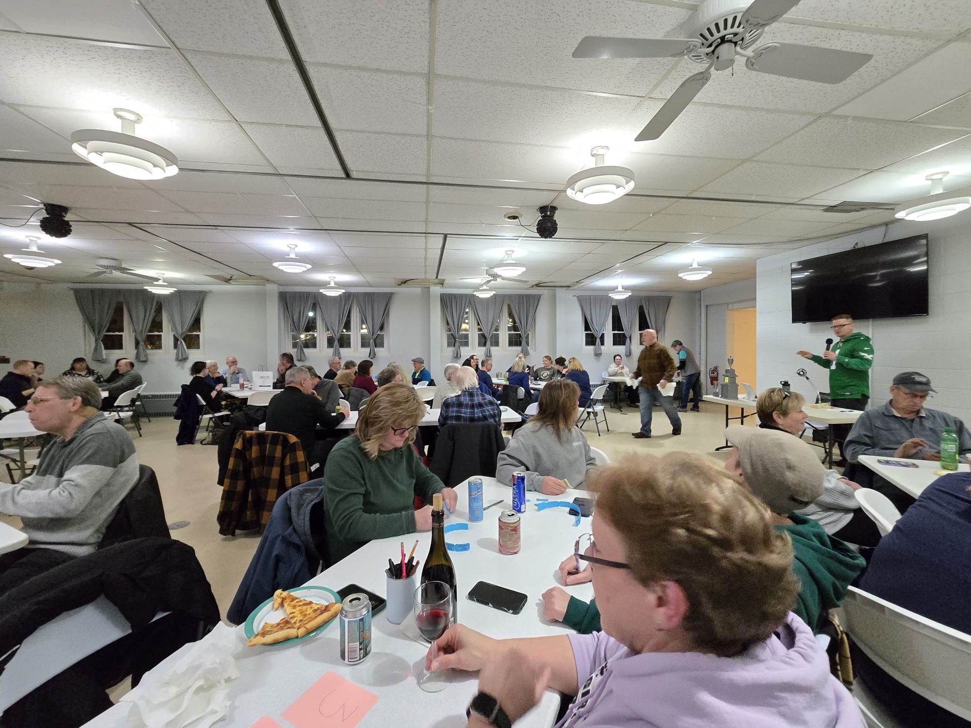 A group of people are sitting at tables in a large room.