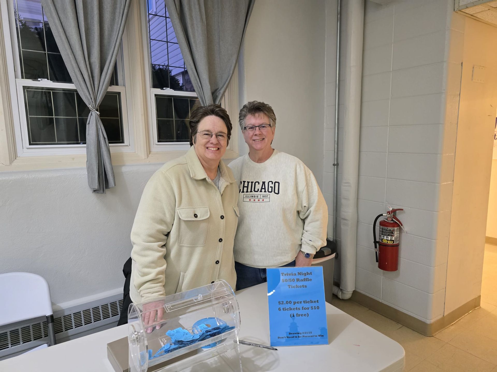 Two women are posing for a picture in front of a table with a sign that says heart on it.
