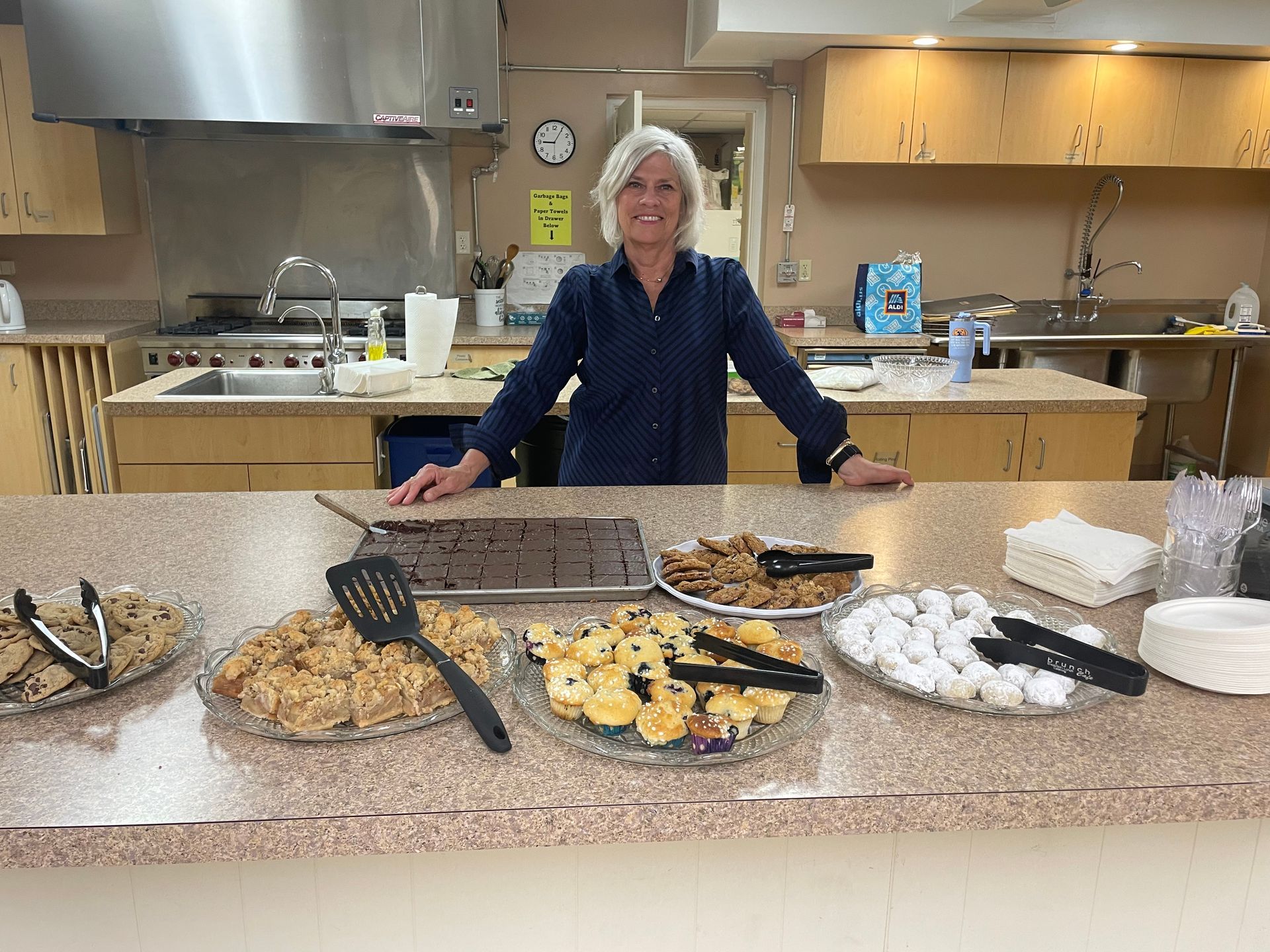A woman is standing in front of a counter with plates of food on it.