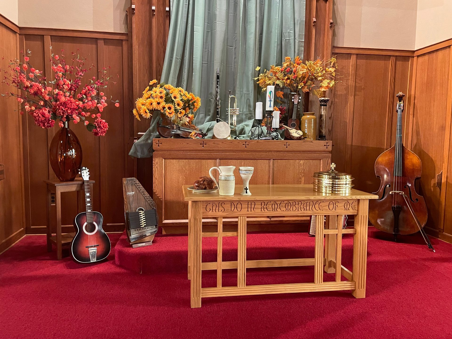 A wooden table with flowers and a guitar on it in a room.