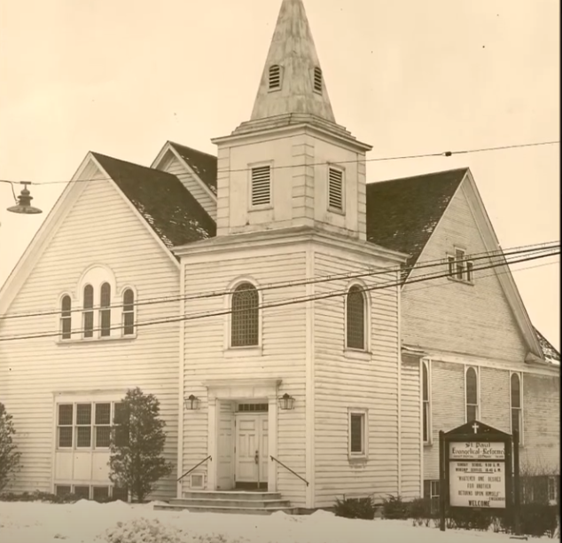 A black and white photo of a church with a steeple