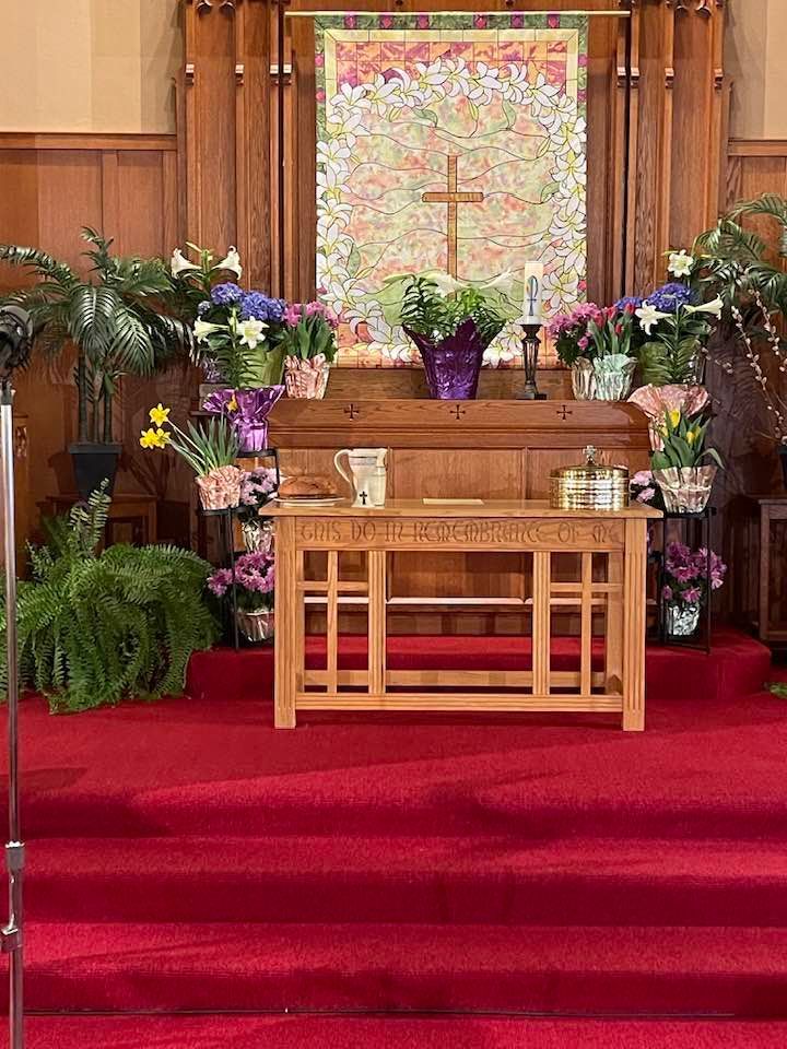 An altar in a church decorated with flowers and plants.