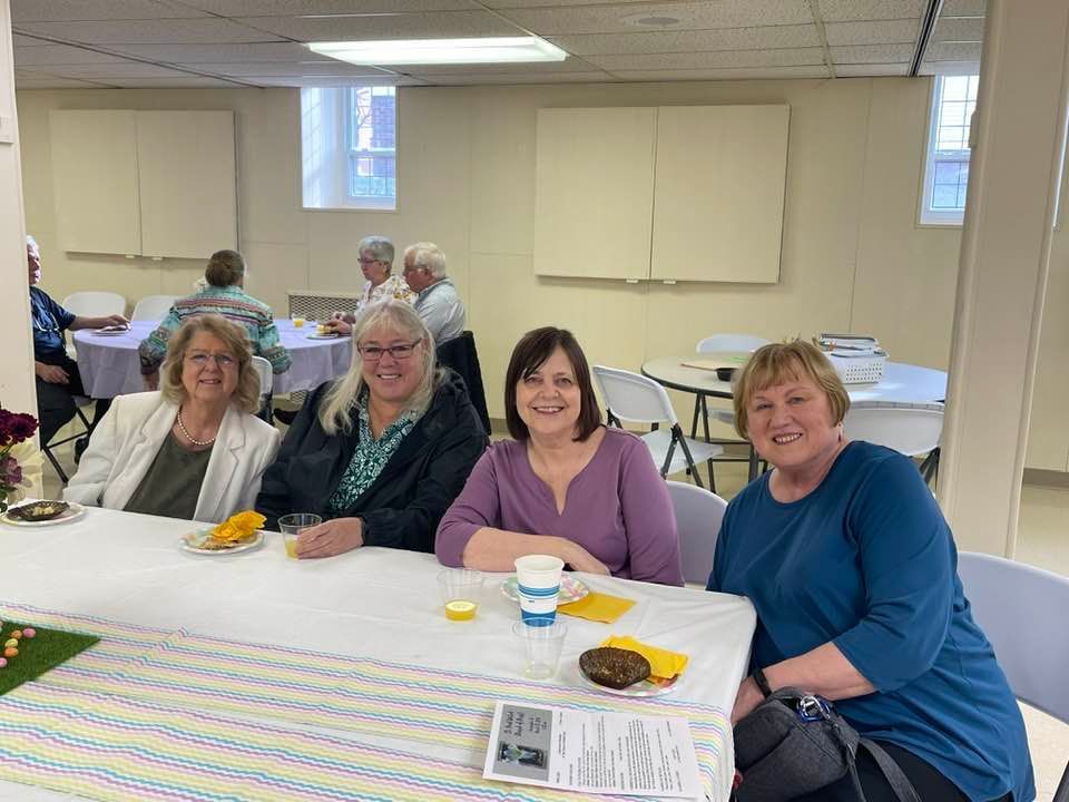 A group of women are sitting at a table in a room.