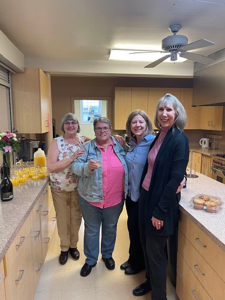 A group of women are posing for a picture in a kitchen.
