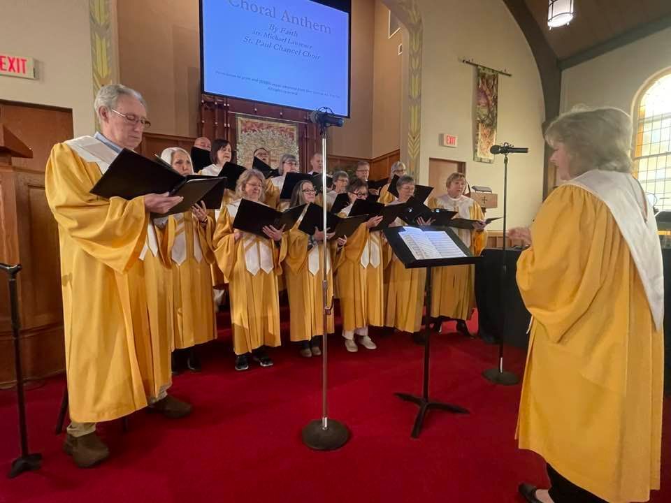 A group of people in yellow robes are singing in a church.