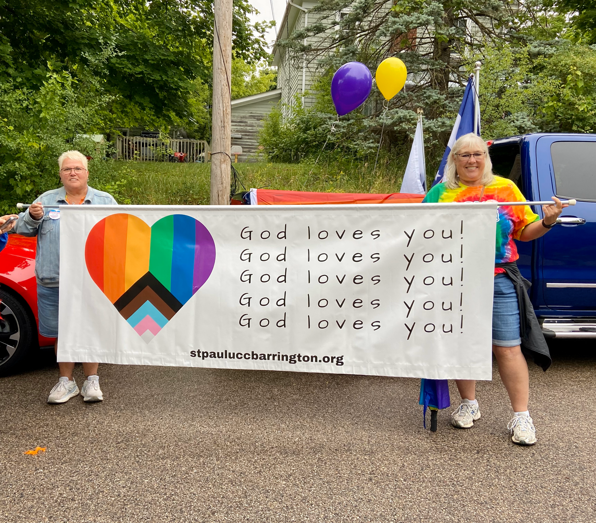 Two people holding a banner that says god loves you