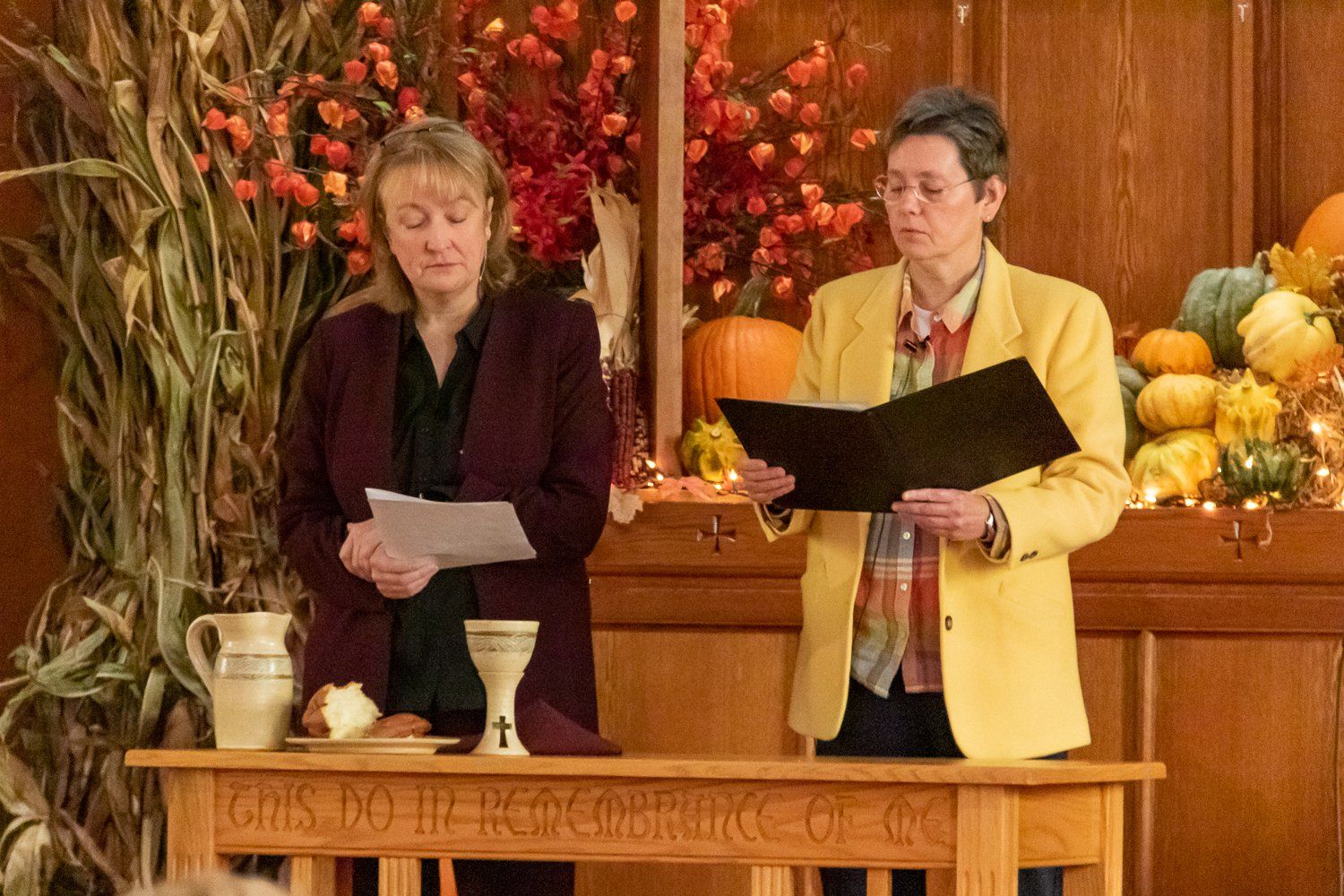 Two women are standing at a table reading a book