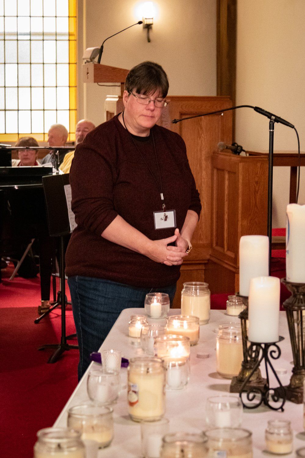 A woman is standing in front of a table with candles on it.