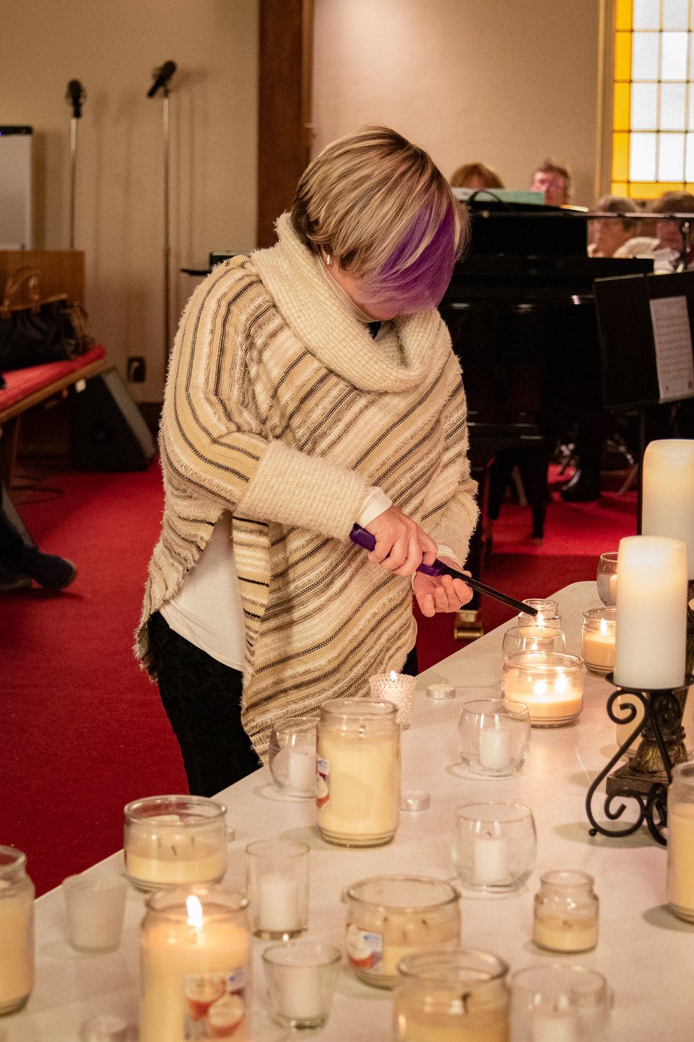A woman is lighting candles on a table in a church.