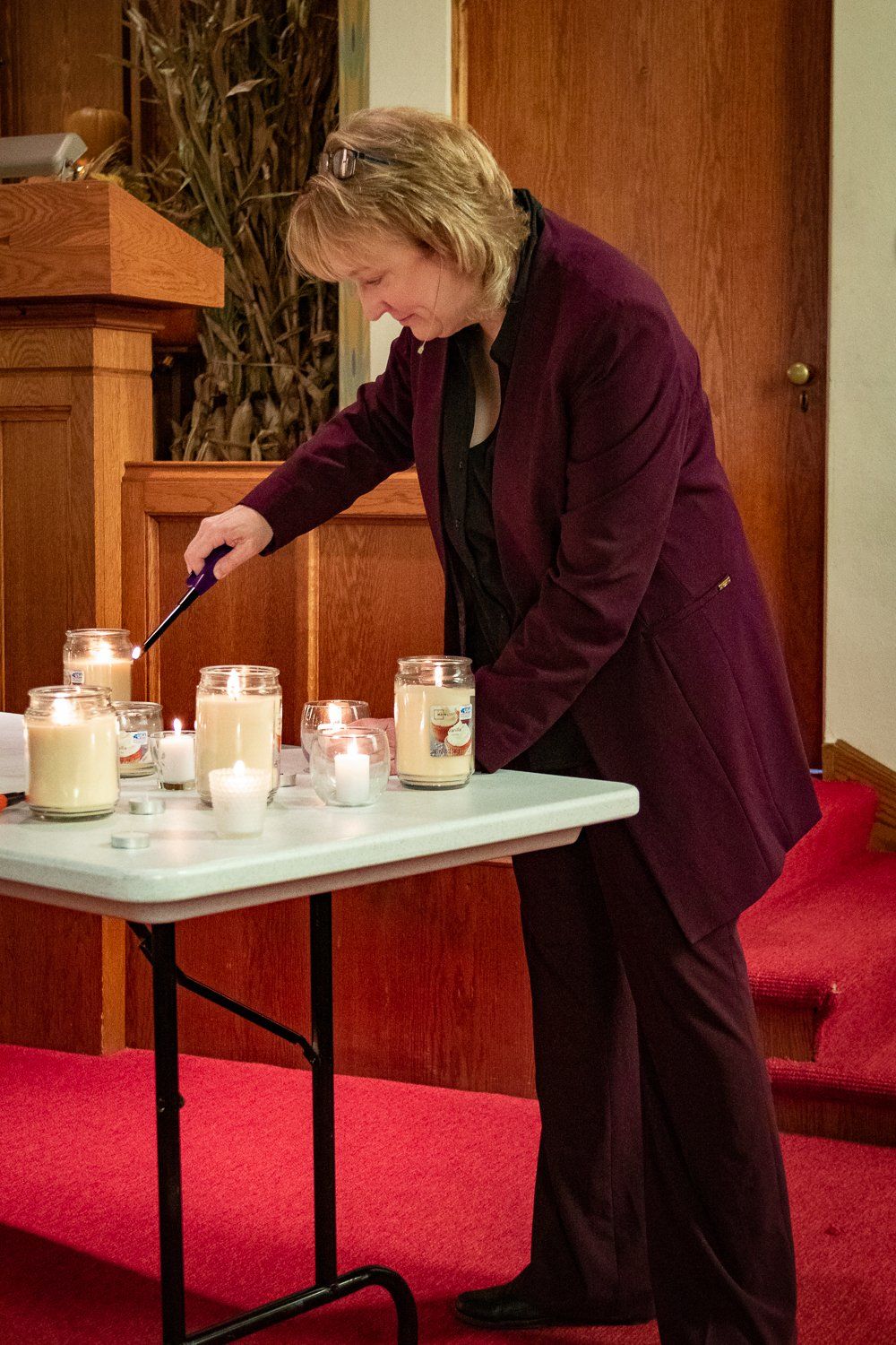 A woman is lighting candles on a table in a church.