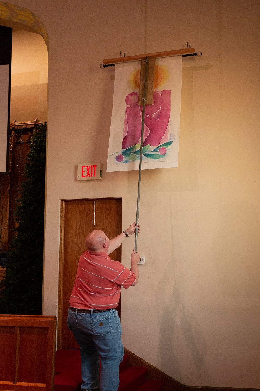 A man is hanging a banner on a wall in a church.