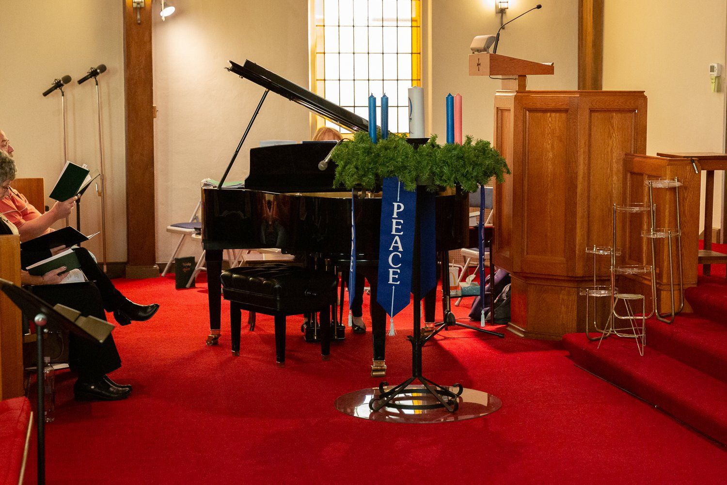 A group of people are sitting in a church with a piano and a podium.