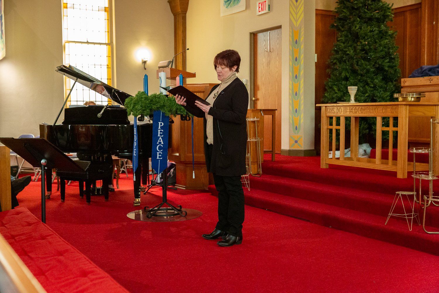 A woman singing in a church with a piano in the background
