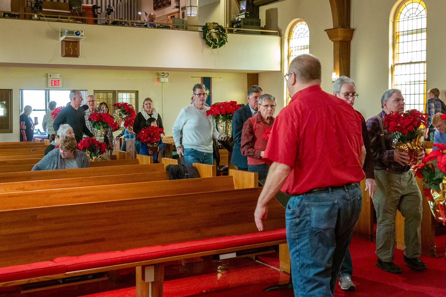 A group of people are standing in a church holding flowers.