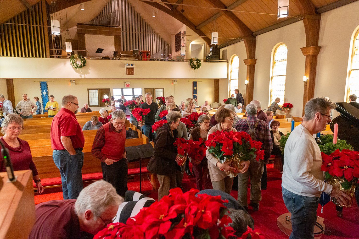 A group of people are standing in a church holding flowers.
